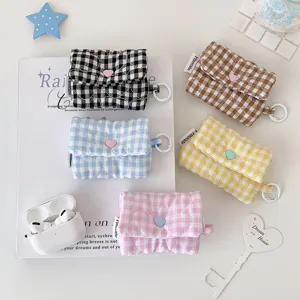 Vue détaillée de l'étui à écouteurs à carreaux matelassé, pochette en tissu avec bouton.
