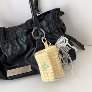 Gros plan sur la mini pochette matelassée à carreaux jaunes avec nœud et perles.
