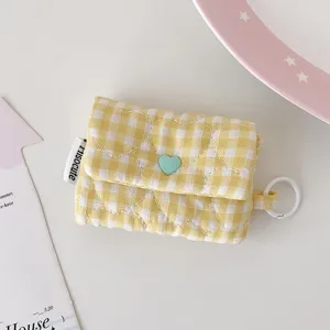 Vue détaillée d'une pochette de rangement en tissu à carreaux jaunes et bouton cœur.