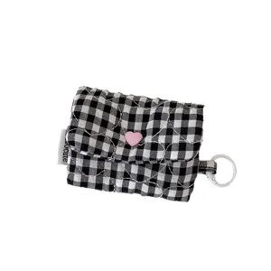 Pochette pour écouteurs matelassée à carreaux noirs et blancs avec bouton cœur rose.