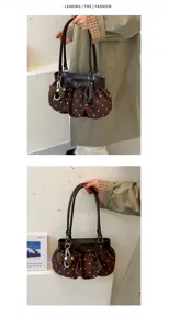 Detailed view of the brown polka dot suede underarm bag with cute bow and pearl charm.