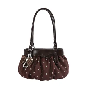 Detailed view of the brown polka dot pleated cloud handbag with bow and pearl pendant.