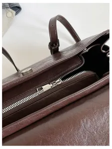 Detailed view of the brown leather shoulder bag interior and metallic zipper hardware.
