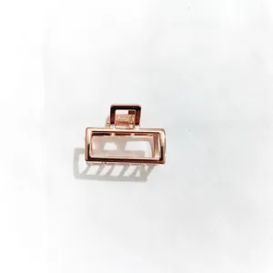 Close-up detail shot of a minimalist rose gold metal hair claw clip, geometric design.