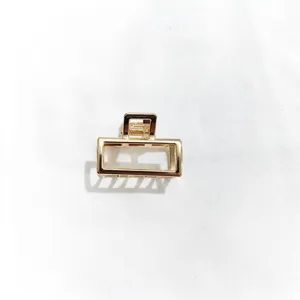 Close-up of a minimalist gold rectangular metal hair claw clip, daily accessory detail.