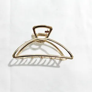 Detail view of a minimal gold metal hair claw clip, elegant geometric shark clip design.