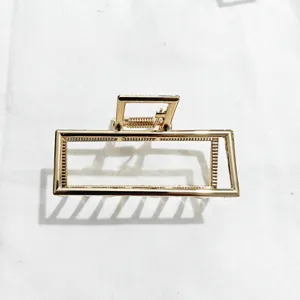 Gold geometric metal hair claw clip detail, minimalist rectangular hair accessory for women.