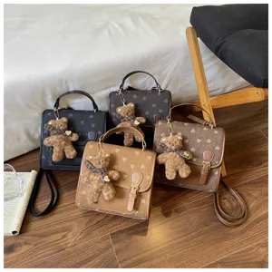 Close-up detail view of stylish mini backpacks featuring cute bear pendants and chic heart patterns.