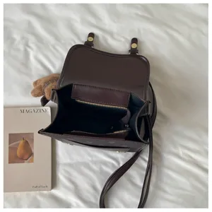 Dark brown PU leather mini backpack detail showing interior storage pocket and double straps.