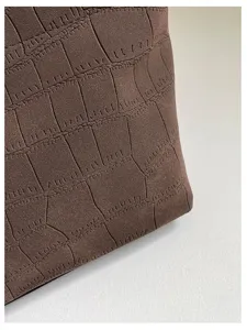 Primo piano della texture goffrata coccodrillo marrone della borsa tote con finitura elegante.