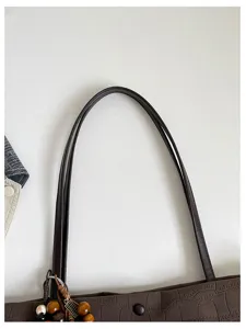 Dettaglio manico borsa shopper marrone in pelle testurizzata con grazioso ciondolo di perle.