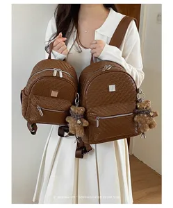 Detail view of woven commuter backpack with cute bear pendant and retro brown leather design.