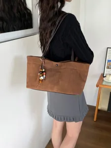 Dettaglio borsa shopper stampa coccodrillo marrone, elegante borsa a spalla con ciondolo.