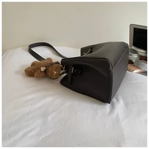 Dark brown leather shoulder bag detail view showing rich texture and cute bear pendant