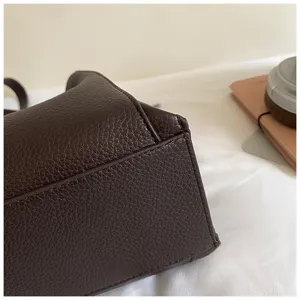 Detailed shot of brown leather handbag displaying fine stitching and pebbled texture design.