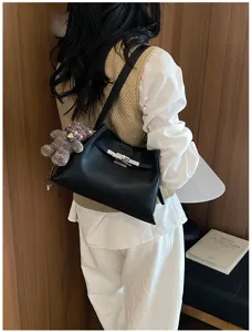 Detailed view of women's black leather shoulder bag with chic hardware and cute bear charm.