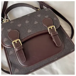 Detail view of a stylish women's contrast backpack with heart pattern and retro buckles.