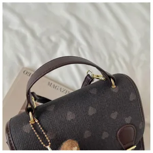 Detailed view of women's autumn winter brown mini backpack with heart pattern and leather handle.