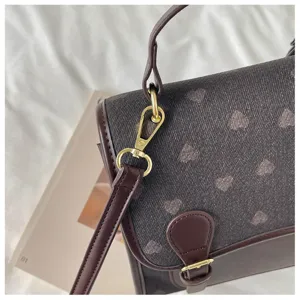 Chic heart print shoulder bag with brown leather trim and gold hardware, stylish daily accessory.