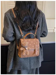 Detailed view of autumn winter fashion women brown backpack with heart print and cute bear pendant.