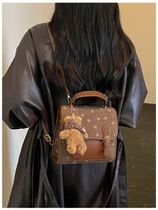 Detailed view of fashionable brown color-block backpack with cute fuzzy bear plush pendant.
