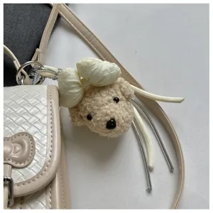 Vista detallada del colgante de bolso de osito de peluche mullido con lazo crema para mochilas