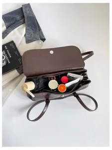 Dark brown leather shoulder bag interior detail showing large capacity with daily items inside.
