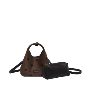 Détail en gros plan du sac porté épaule croissant à pois marron et de sa pochette noire.