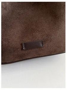 Gros plan detail sac hobo daim marron avec couture patch en cuir et texture fine elegance.