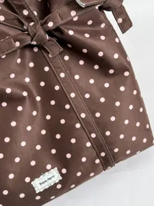 Brown pink polka dot fabric shoulder bag detail shot with cute tied strap and label.
