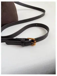 Gros plan de la sangle de sac à bandoulière marron foncé avec boucle métallique.