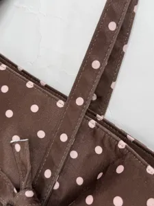 Brown polka dot shoulder bag close-up detail showcasing soft fabric and cute bow accent.