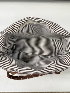 Stylish brown striped interior tote bag with polka dot strap and plush charm accent.