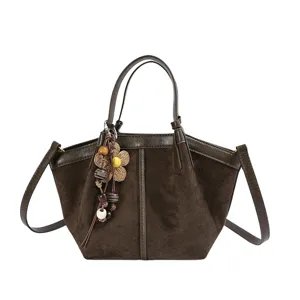 Brown suede bucket bag with shoulder strap and chic floral charm variant for daily use.