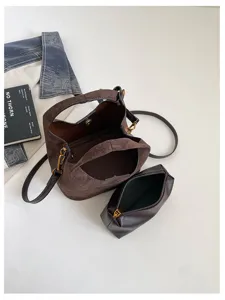 Détail de sac porté épaule croissant en daim marron, sac hobo élégant avec petite pochette.