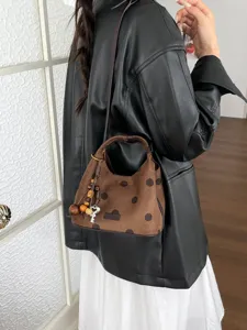 Détail de sac à main croissant en daim marron, sac porté épaule élégant à pois, accessoire automne