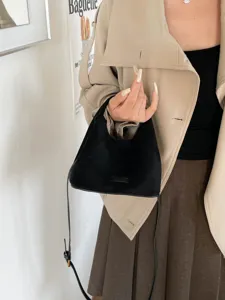 Gros-plan d'un élégant sac hobo épaule en suédine noire avec fine bandoulière, style minimaliste.