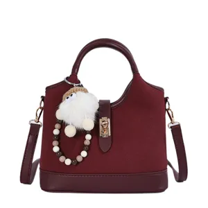 Burgundy bucket bag detail, premium suede texture, metal lock closure, stylish keyring.
