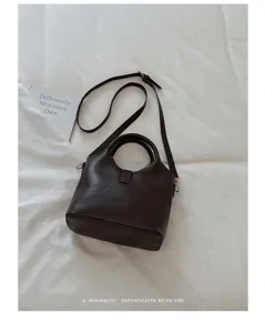 Detailed view of dark brown leather bucket bag handle and strap texture close up.