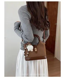 Detail view of a retro brown bucket bag with plush charm and bead strap for women.