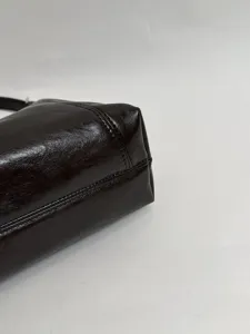 Brown leather shoulder bag detail shot, minimalist underarm bag craftsmanship close up.