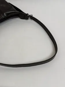 Close-up detail of dark brown faux leather shoulder bag strap and silver metal buckle.