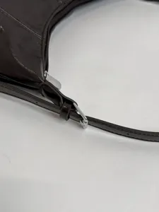 Detailed view of the dark brown leather shoulder bag featuring a metal zipper and adjustable strap.