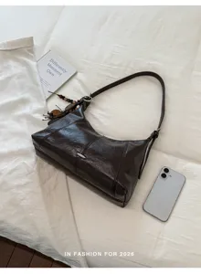 Detailed view of a stylish brown leather hobo shoulder bag with chic charms and clean styling.