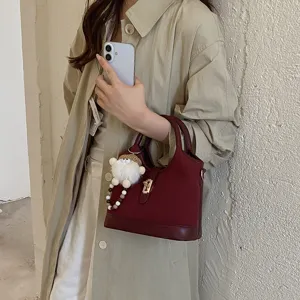 Chic retro bucket handbag for women, elegant commuter shoulder bag with metal lock and plush charm.