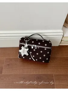 Detailed view of vintage brown polka dot handbag featuring cute star charm and texture.