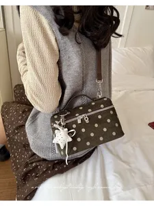 Detailed lifestyle view of a retro polka dot structured handbag with charm in cozy setting.
