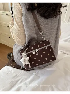 Detailed view of vintage brown polka dot shoulder bag with stylish star pendant.