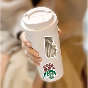Close-up view of decorative vintage stickers applied on a white travel tumbler cup detail.