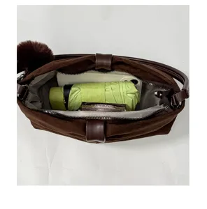 Dettaglio borsa in camoscio marrone, interno grande capacità, fiocco elegante e peluche.